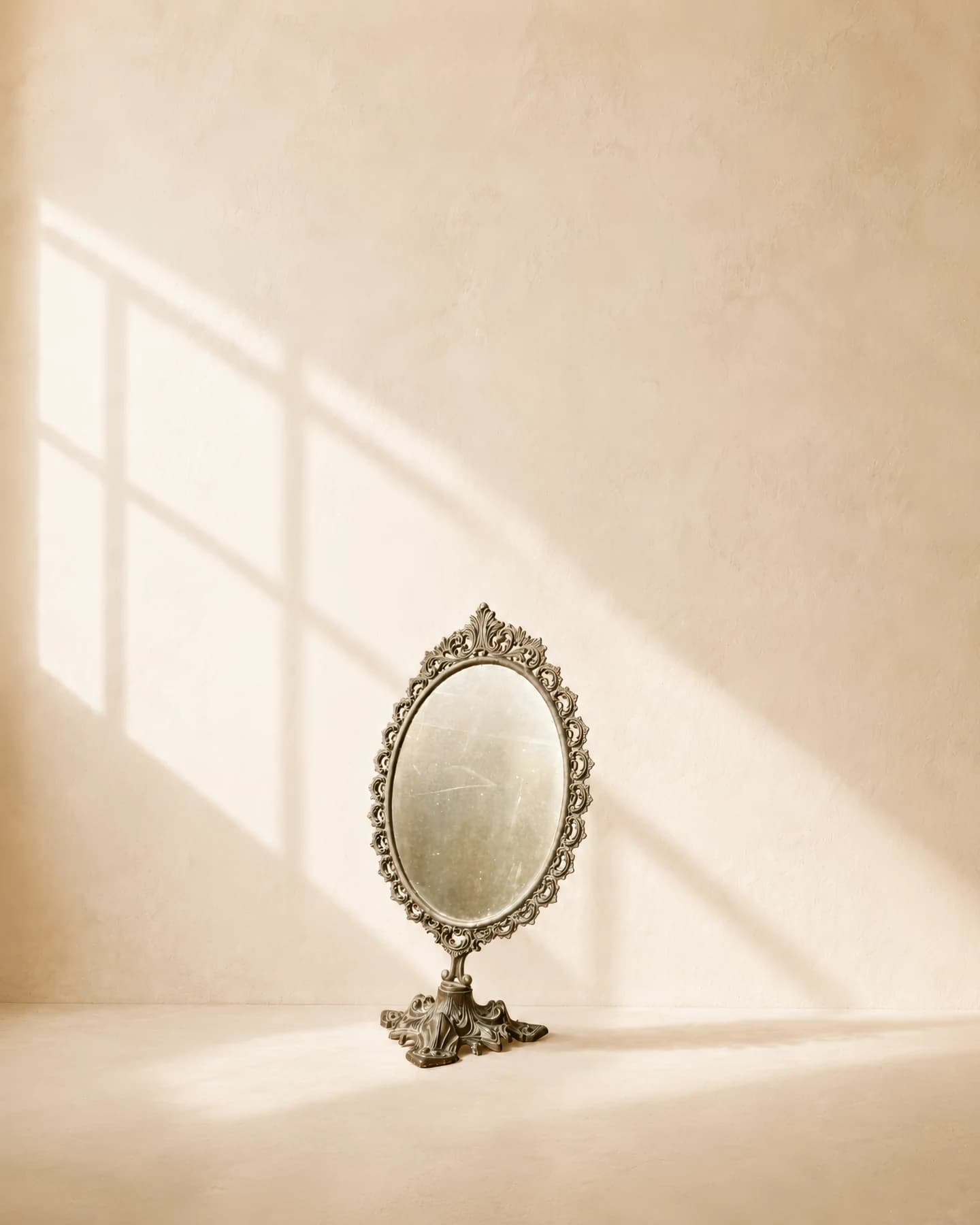 Book-style image of an ornate oval mirror in warm light.